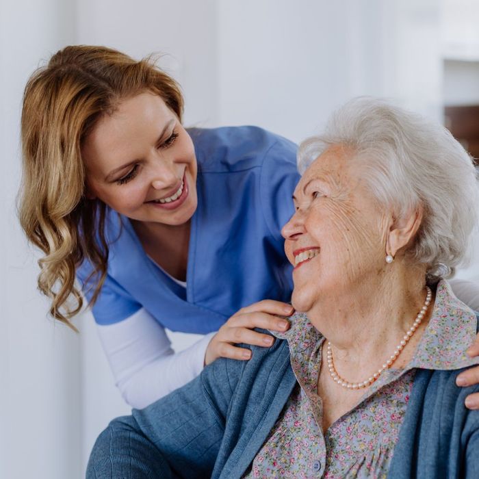 A nurse is talking to an elderly woman who is sitting in a chair.