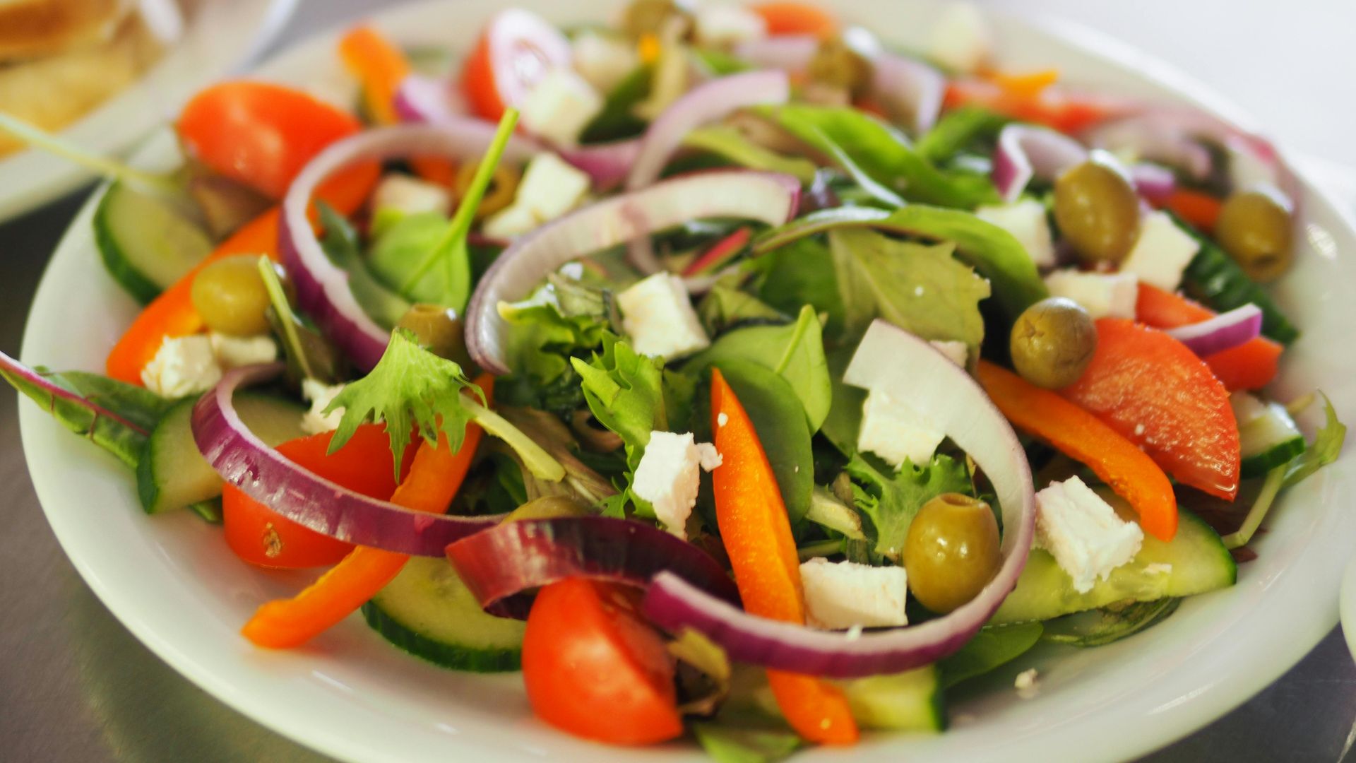 Fresh salad with tomatoes, cucumber, olives, red onion, feta cheese, and bell pepper.