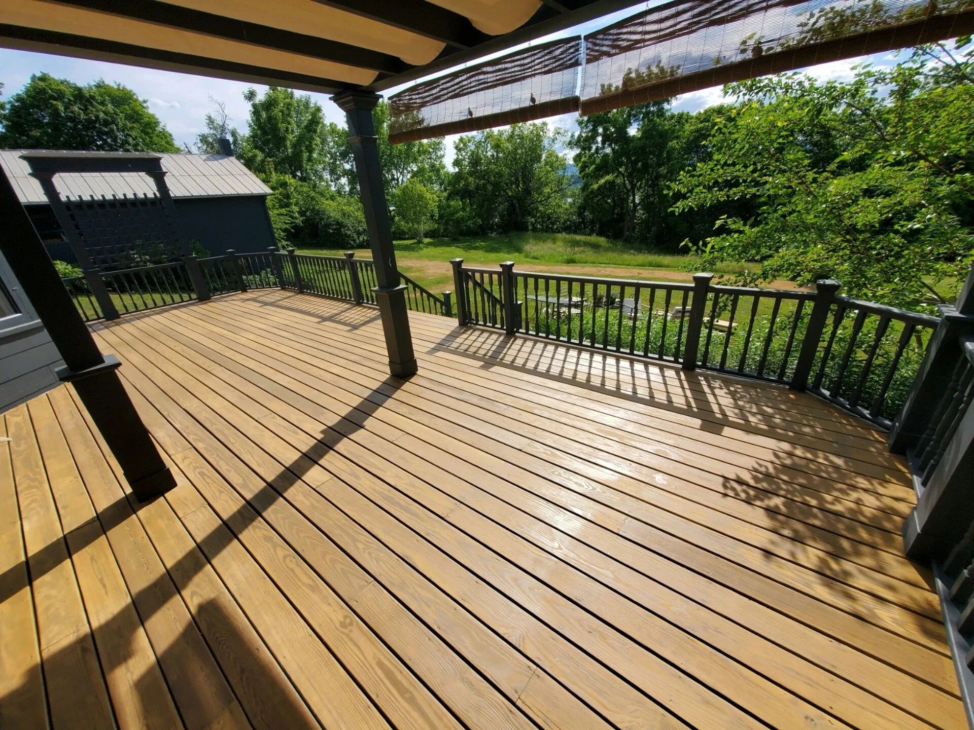 A large wooden deck with a black railing and a canopy.
