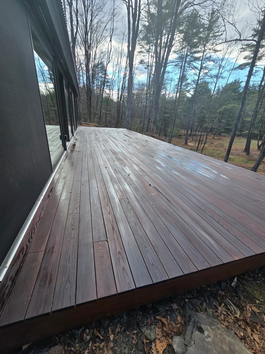 A large wooden deck is sitting in the middle of a forest.