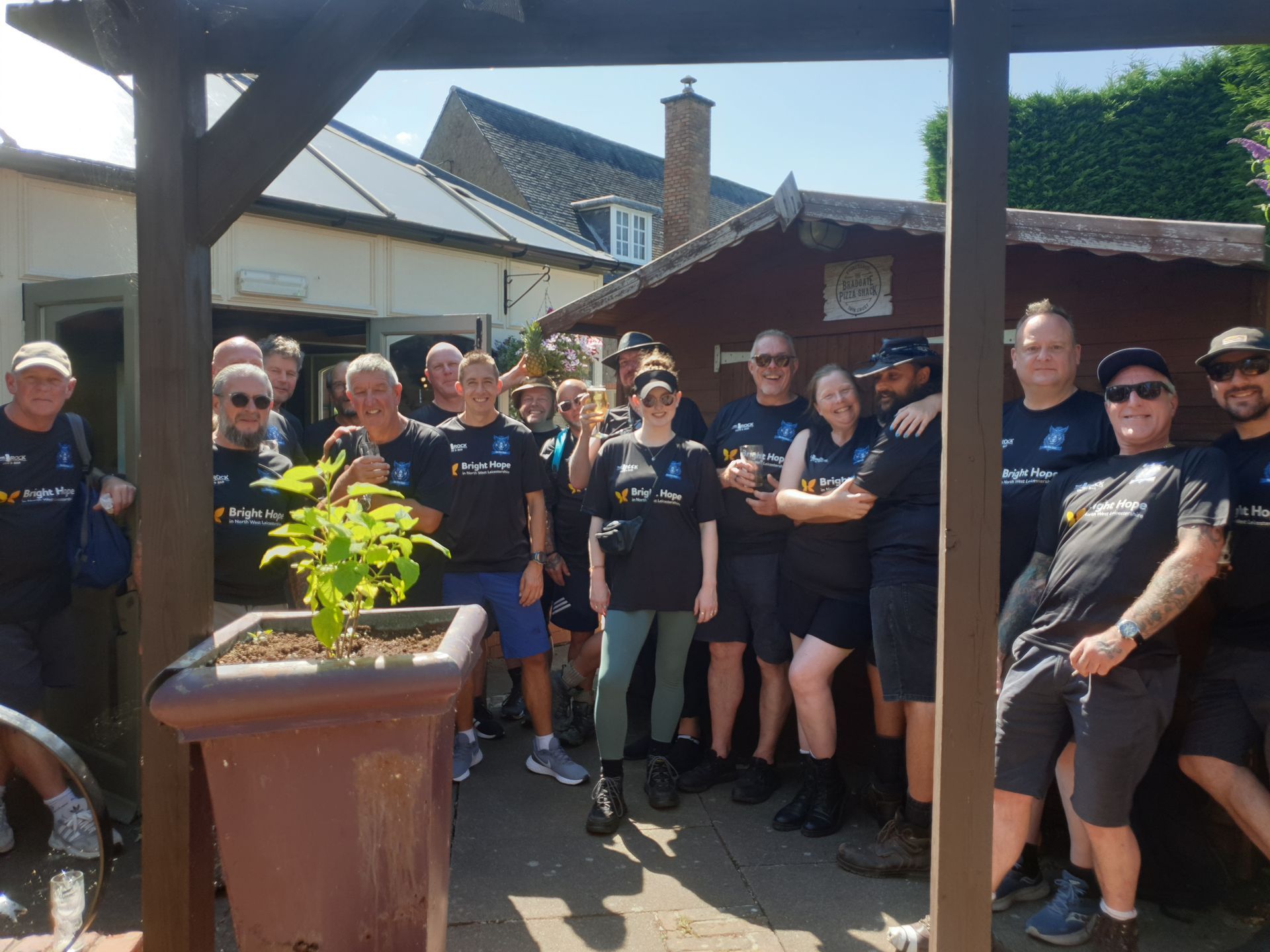 Group of people in black shirts pose outdoors, some with arms around each other.