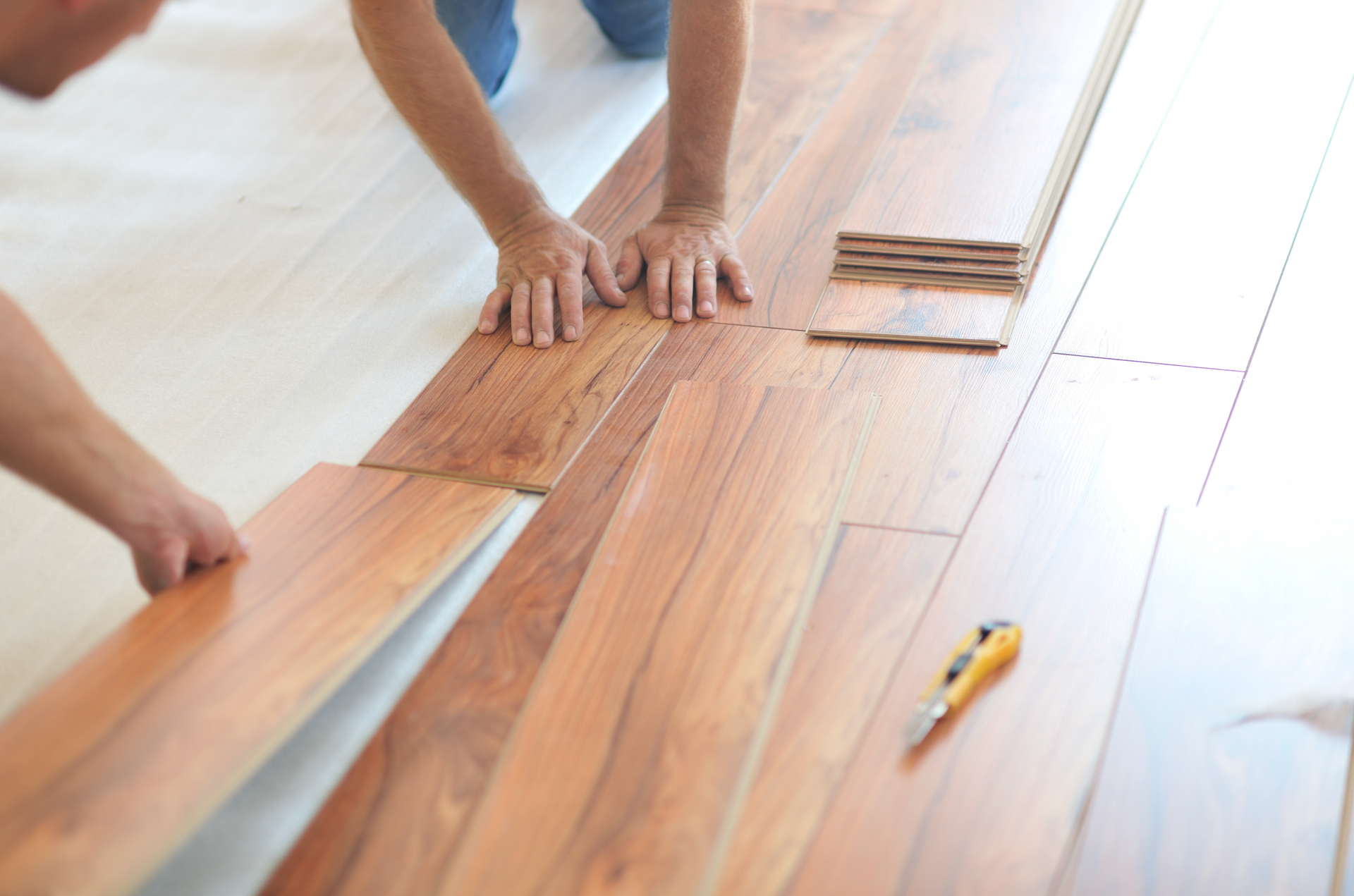 A man is installing a wooden floor in a room.