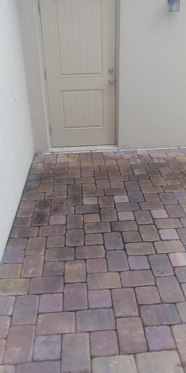Stone patio leading to a tan door in a beige wall.