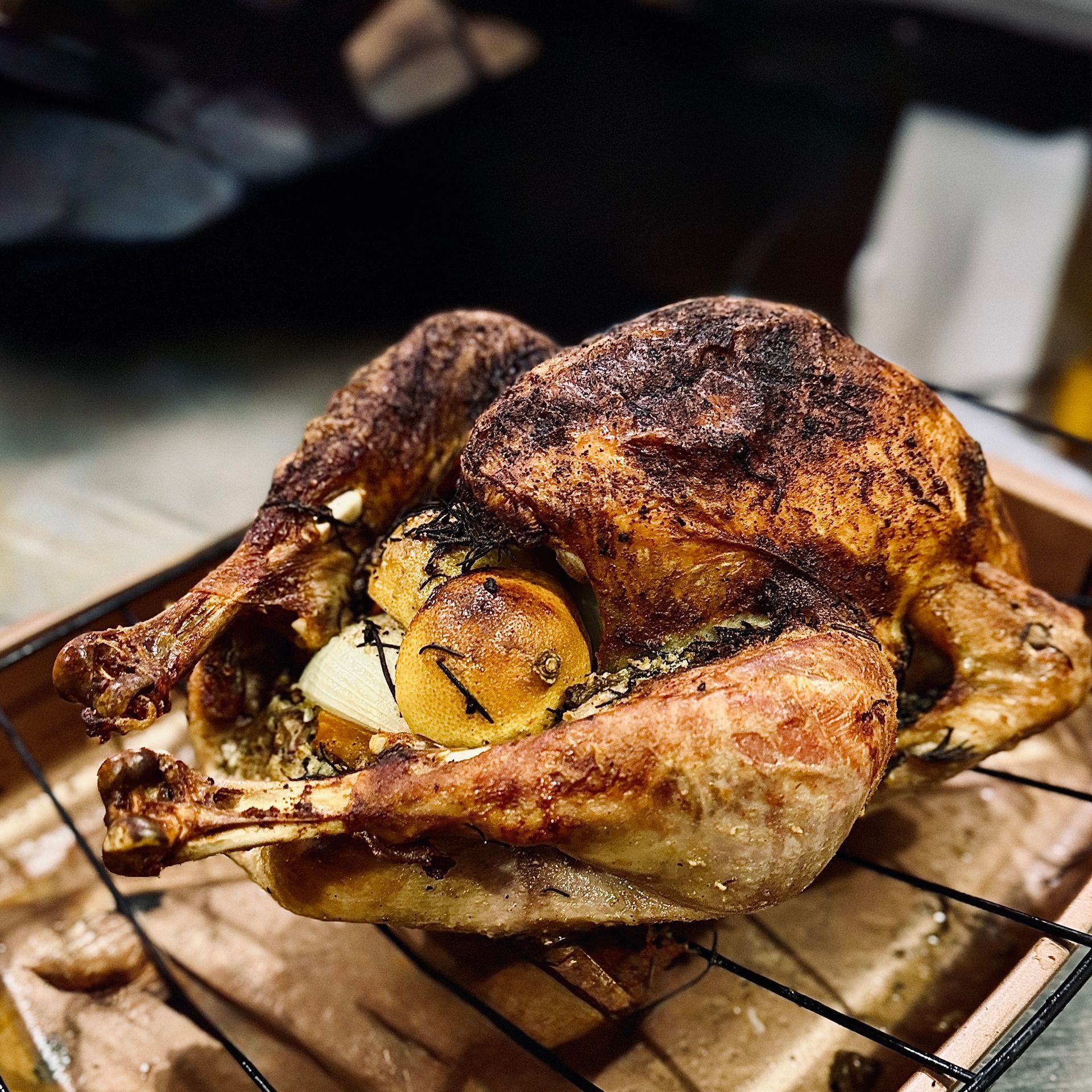 Roasted whole chicken with lemon on a wire rack, browned and crispy on a countertop.