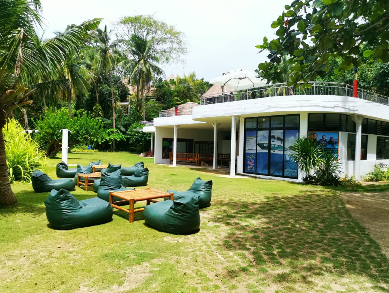 Dive center in green lawn, and outdoor seating amid lush tropical trees