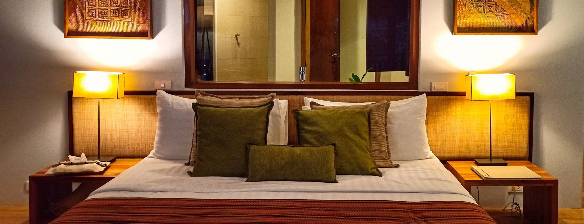 Cozy hotel bedroom with a neatly made bed, warm bedside lamps, and framed wall art