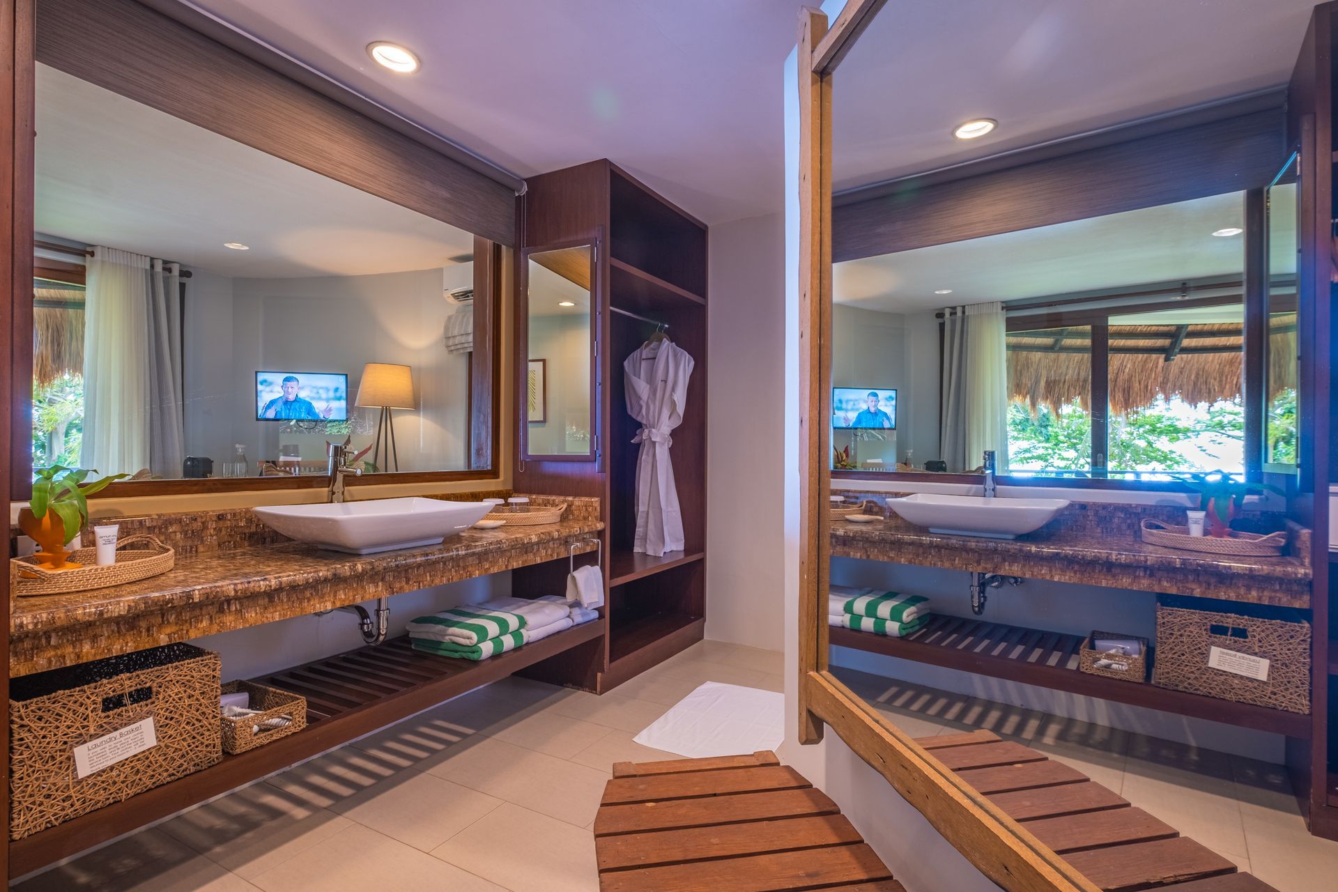 Modern bathroom vanity with double sinks, large mirrors, and stone countertops in a bright hotel-like suite