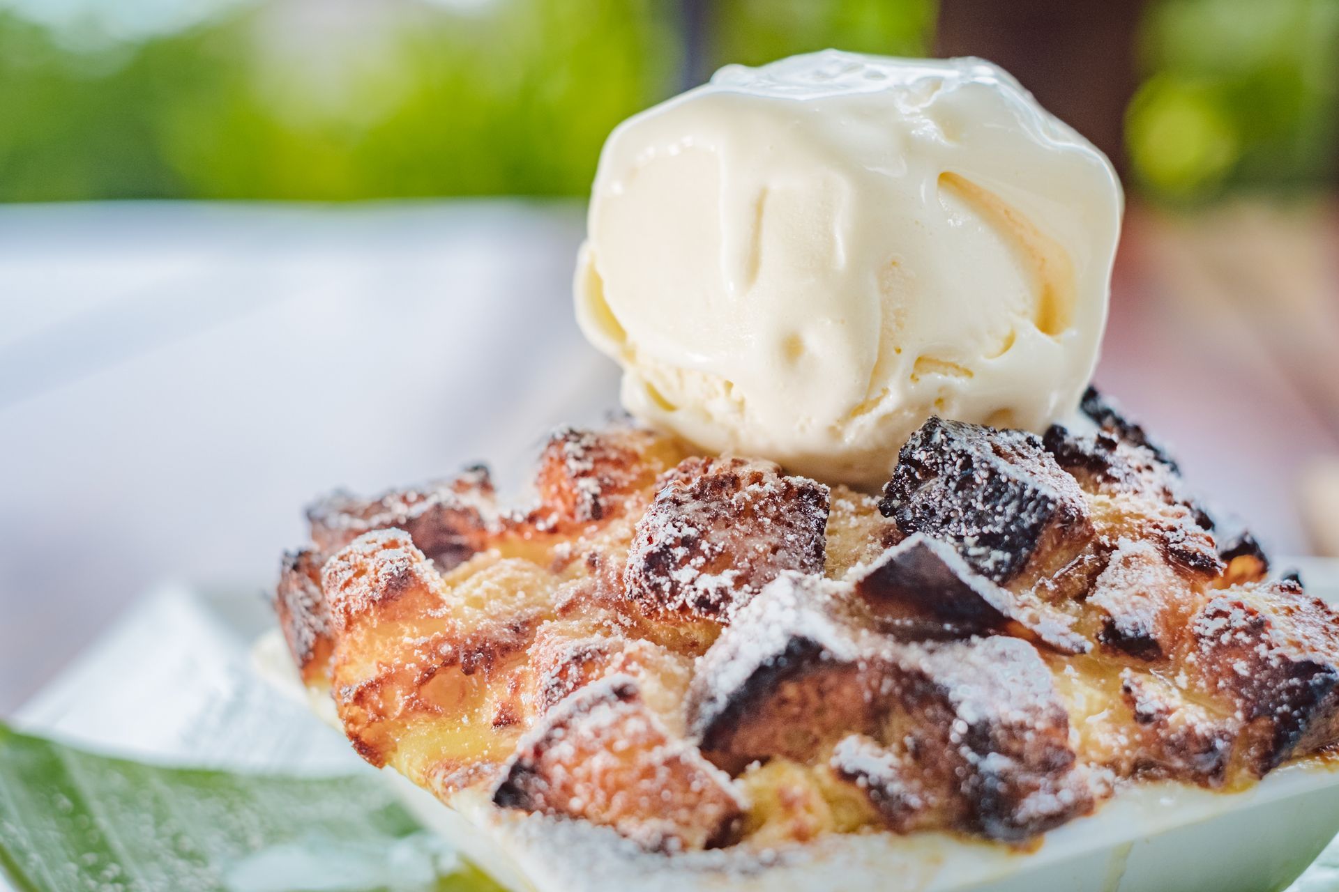 Waffle topped with a scoop of vanilla ice cream and powdered sugar on a plate