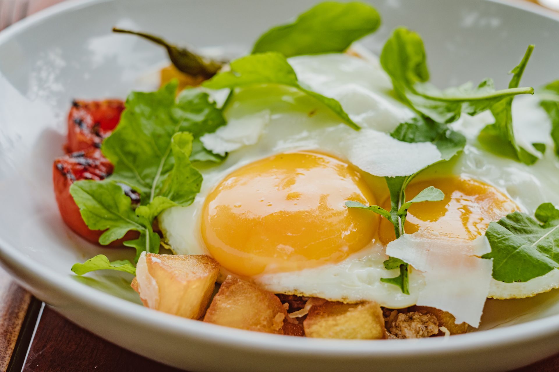 Plated fried eggs with greens and roasted tomatoes on toast