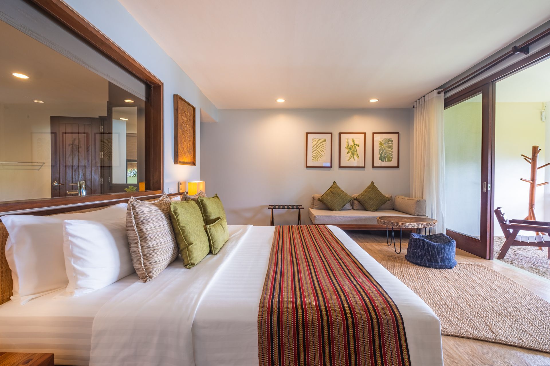Bright modern bedroom with a large bed, wood accents, framed art, and a balcony view