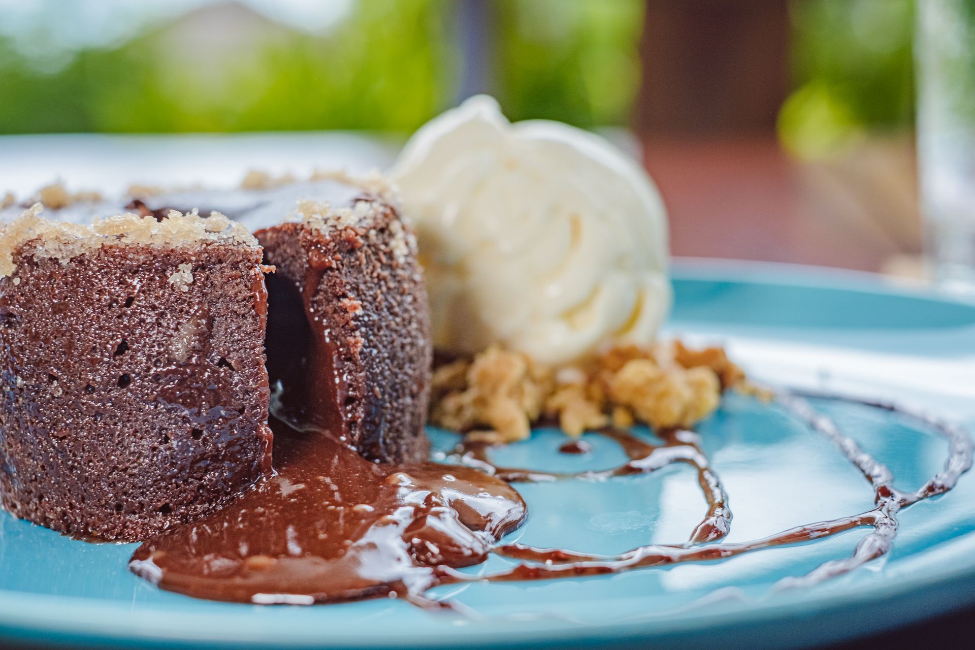 Chocolate lava cake with melting center, whipped cream, and nuts on a blue plate