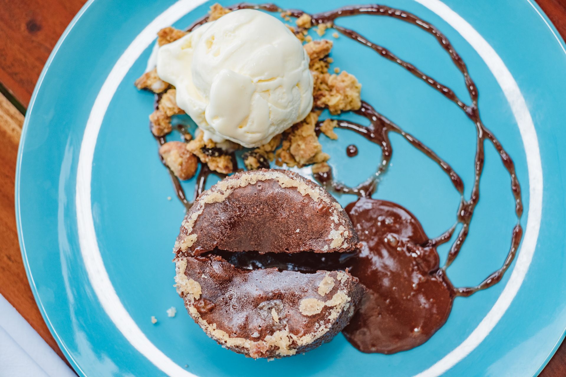 Dessert plate with ice cream, a chocolate lava cake, and chocolate sauce on a blue dish