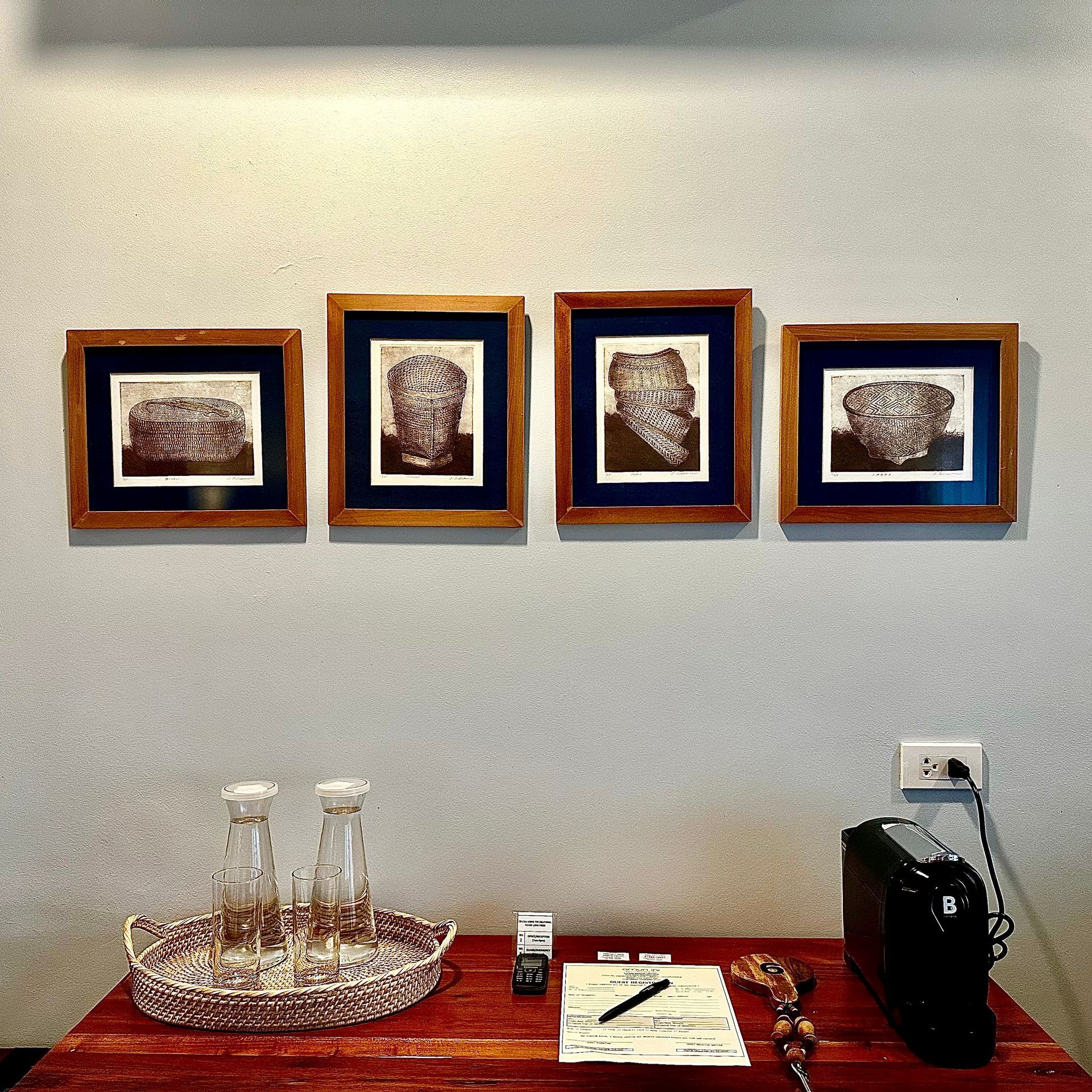 Wall-mounted art above a table with glass bottles, a notebook, and a black bag.