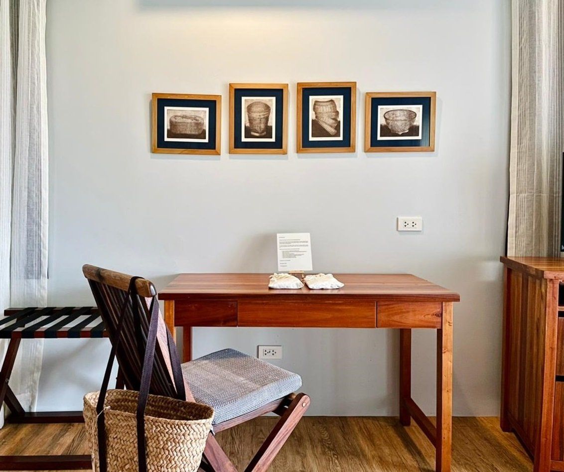 Wooden desk and chair in a minimalist room, with four framed wall photos above it.