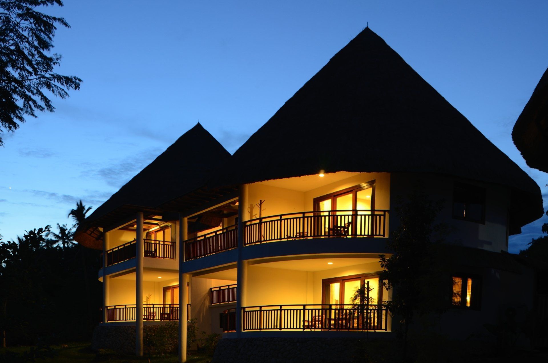 Two-story lodge with glowing balconies at dusk under a blue sky