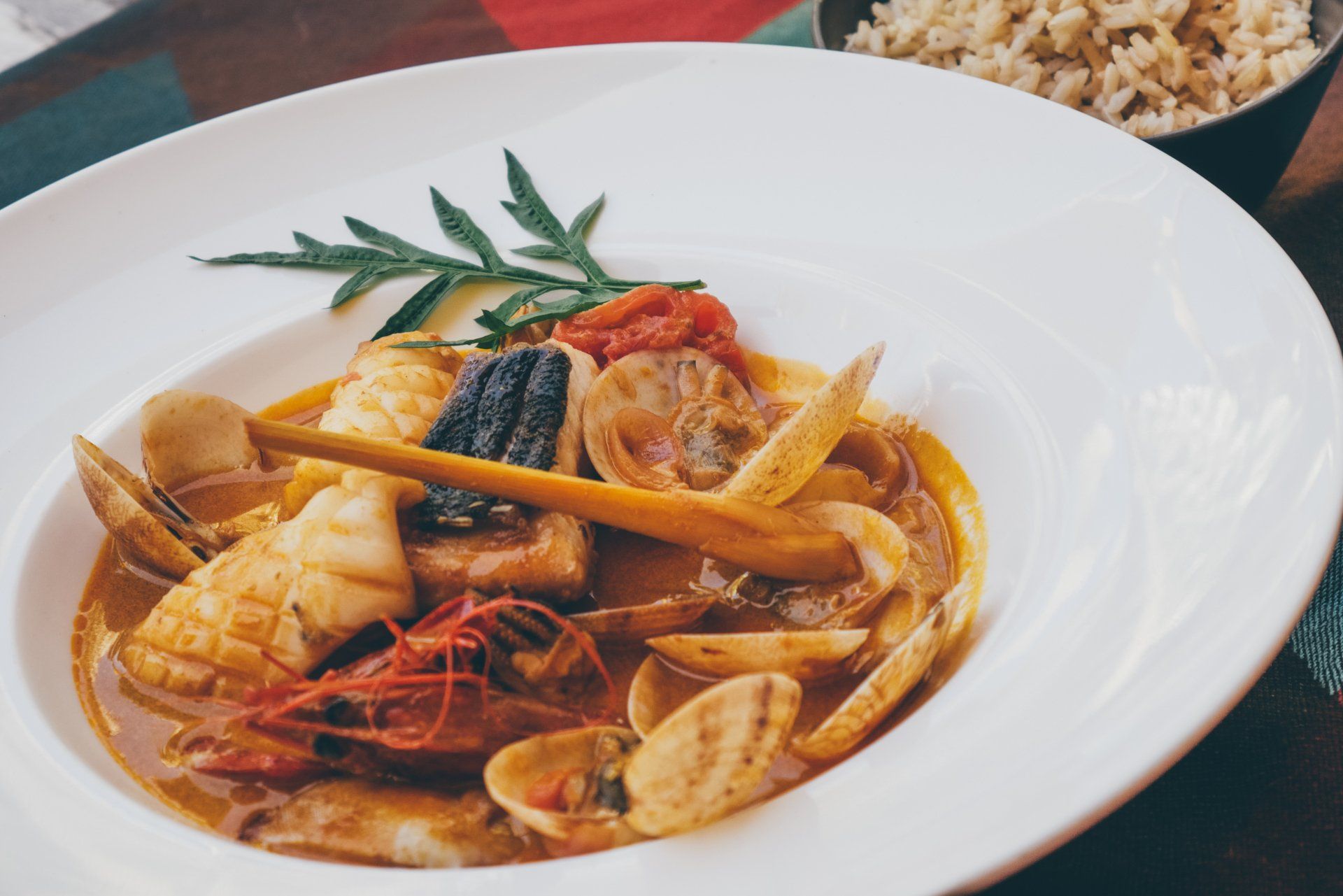 Seafood pasta in a white bowl with clams, shrimp, mussels, and rosemary garnish