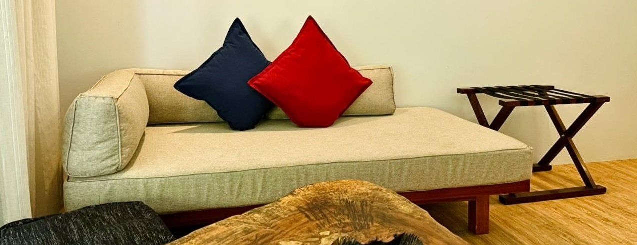 Cream sofa with red and navy cushions beside a small wooden side table on a beige rug.
