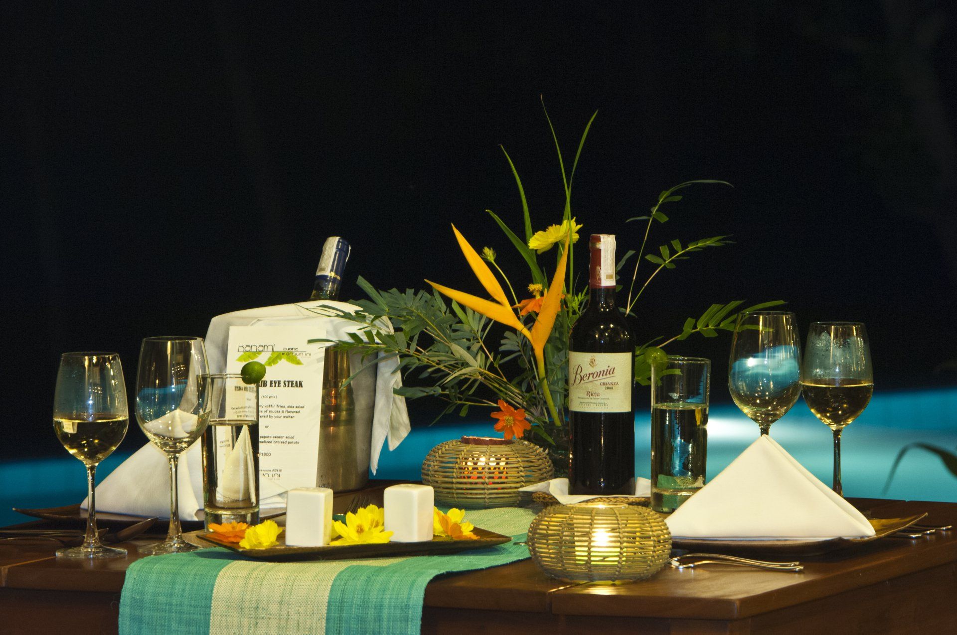 Elegant table setting with wine glasses, candles, flowers, and folded napkins on a dining table