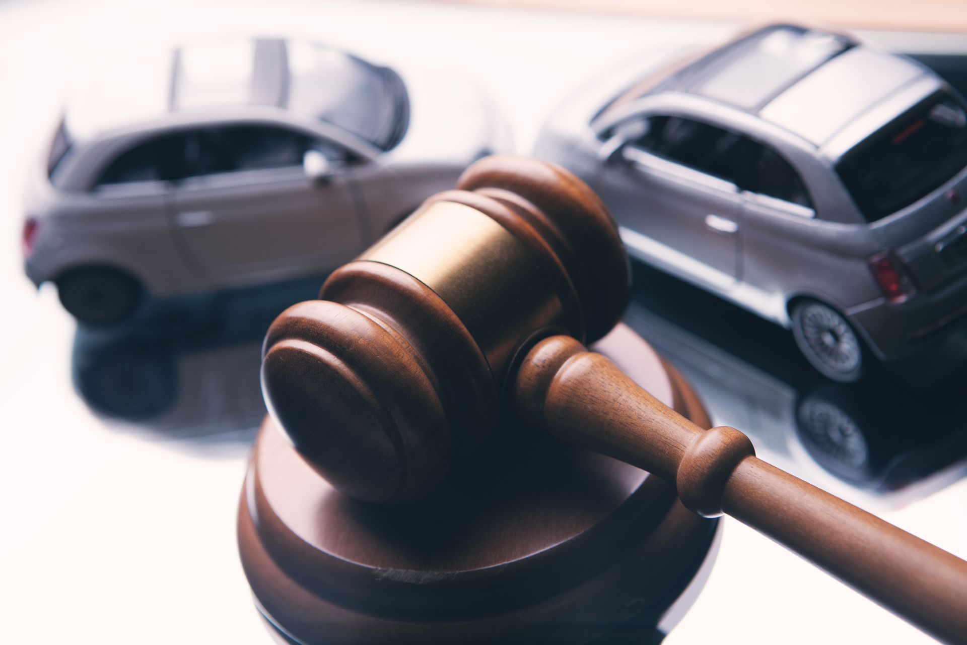 A wooden judge's gavel resting on a block with two miniature toy cars in the background. A wooden judge's gavel resting on a block with two miniature toy cars in the background.