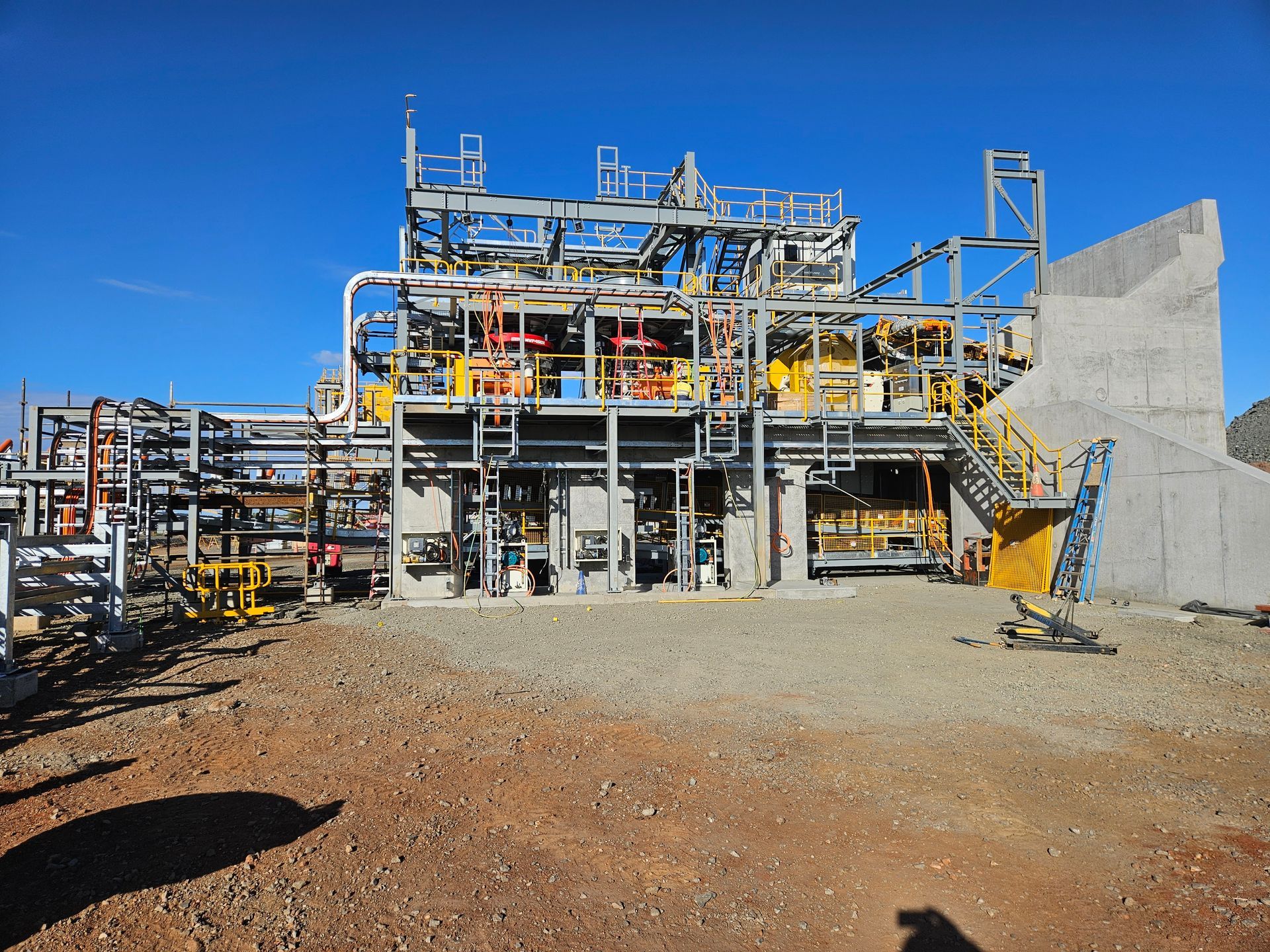 Industrial plant structure with blue steel scaffolding and concrete walls under a clear sky