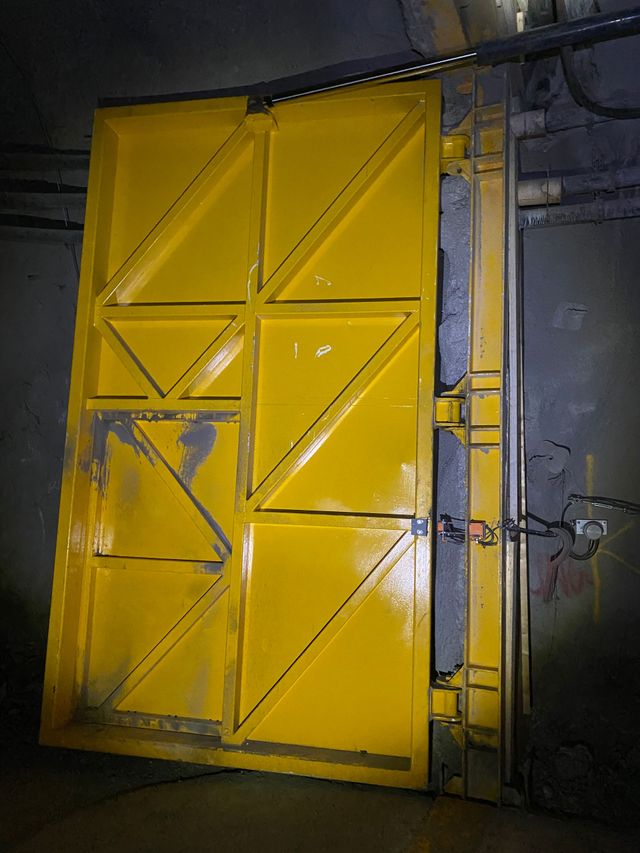 Yellow industrial metal door with diagonal panels, scuffed paint, and a chain lock in a dim corridor — Vent Doors Australia in Bohle, QLD