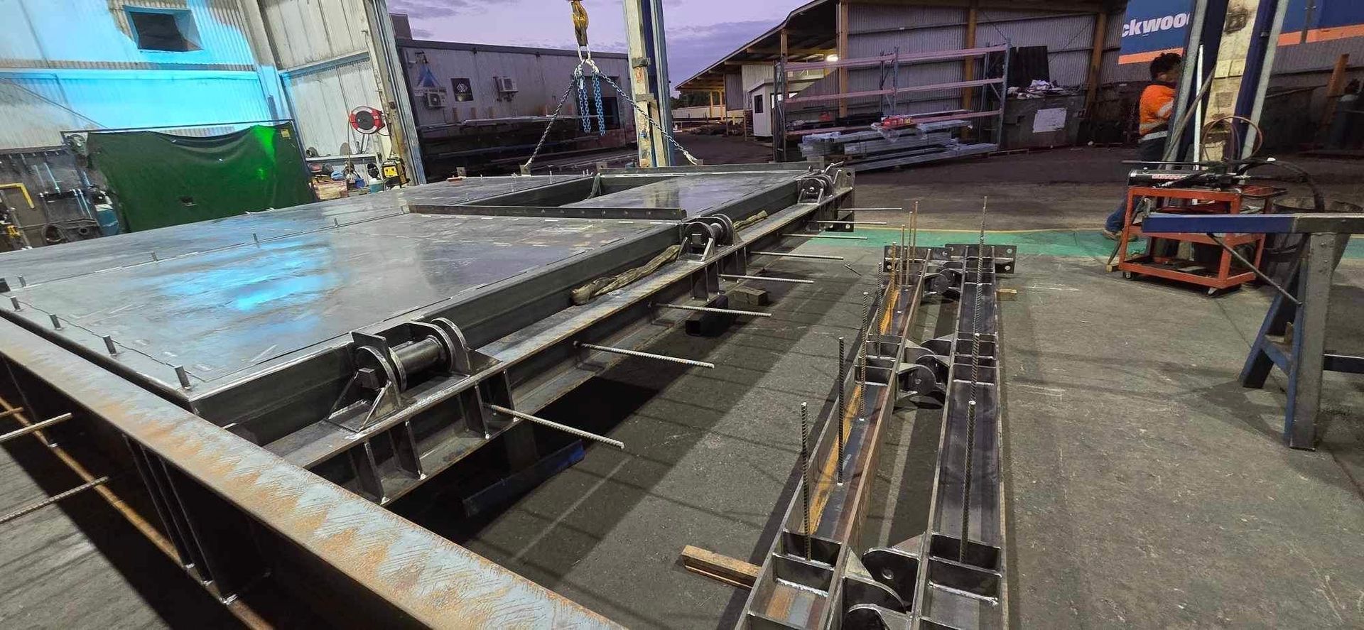 Industrial yard with long metal pipes and steel beams stacked beside a loading area.
