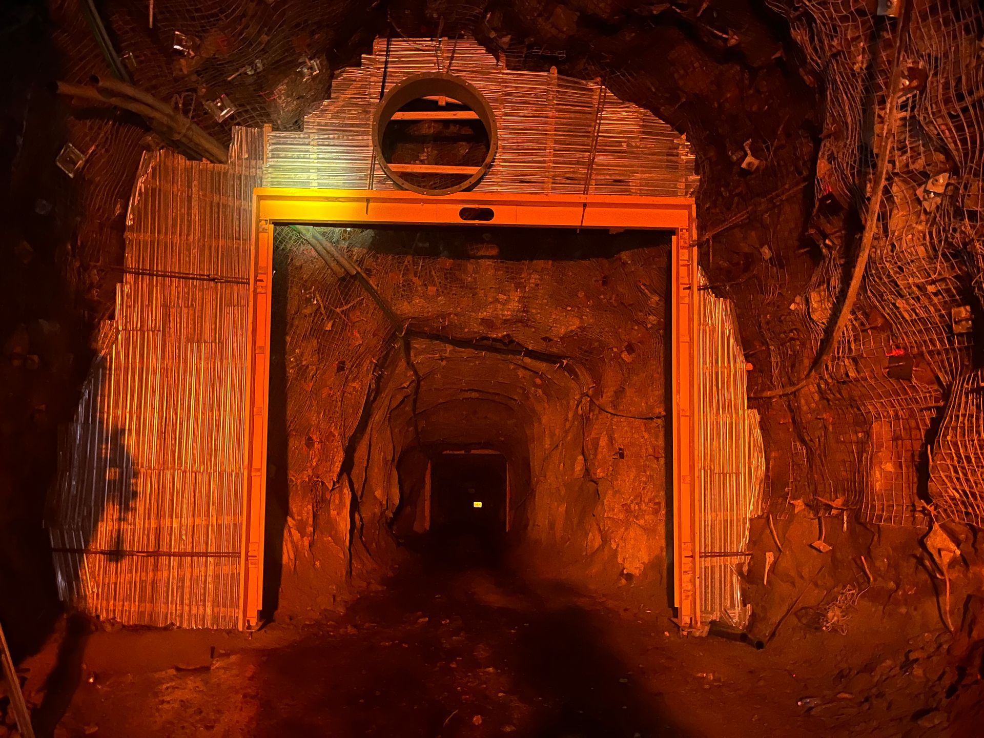 Orange-lit mine tunnel entrance with a dark passage receding into the distance — Vent Doors Australia in Ryan, QLD