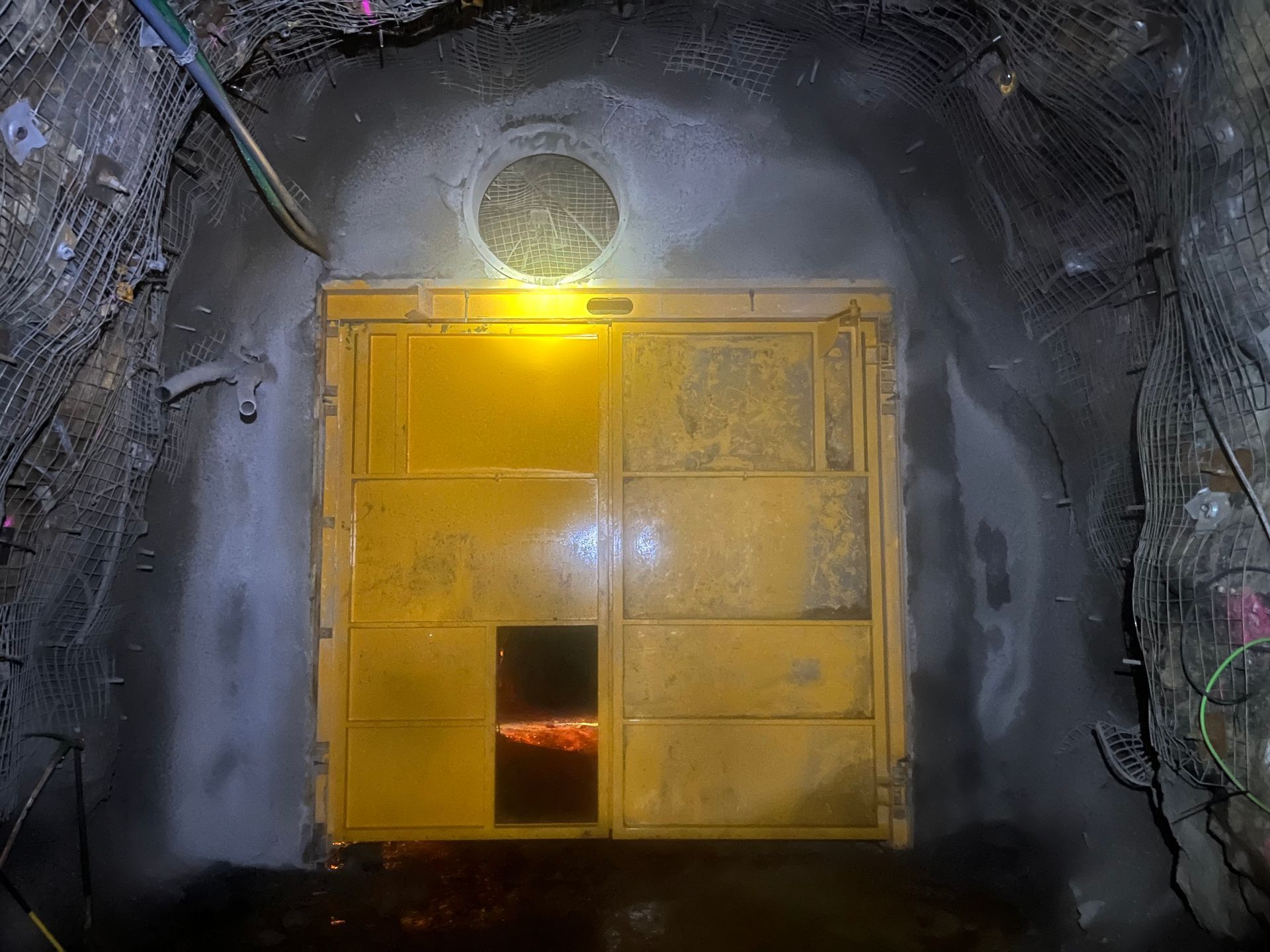 Yellow industrial door at the end of a dim tunnel, lit by a bright overhead lamp — Vent Doors Australia in Ryan, QLD