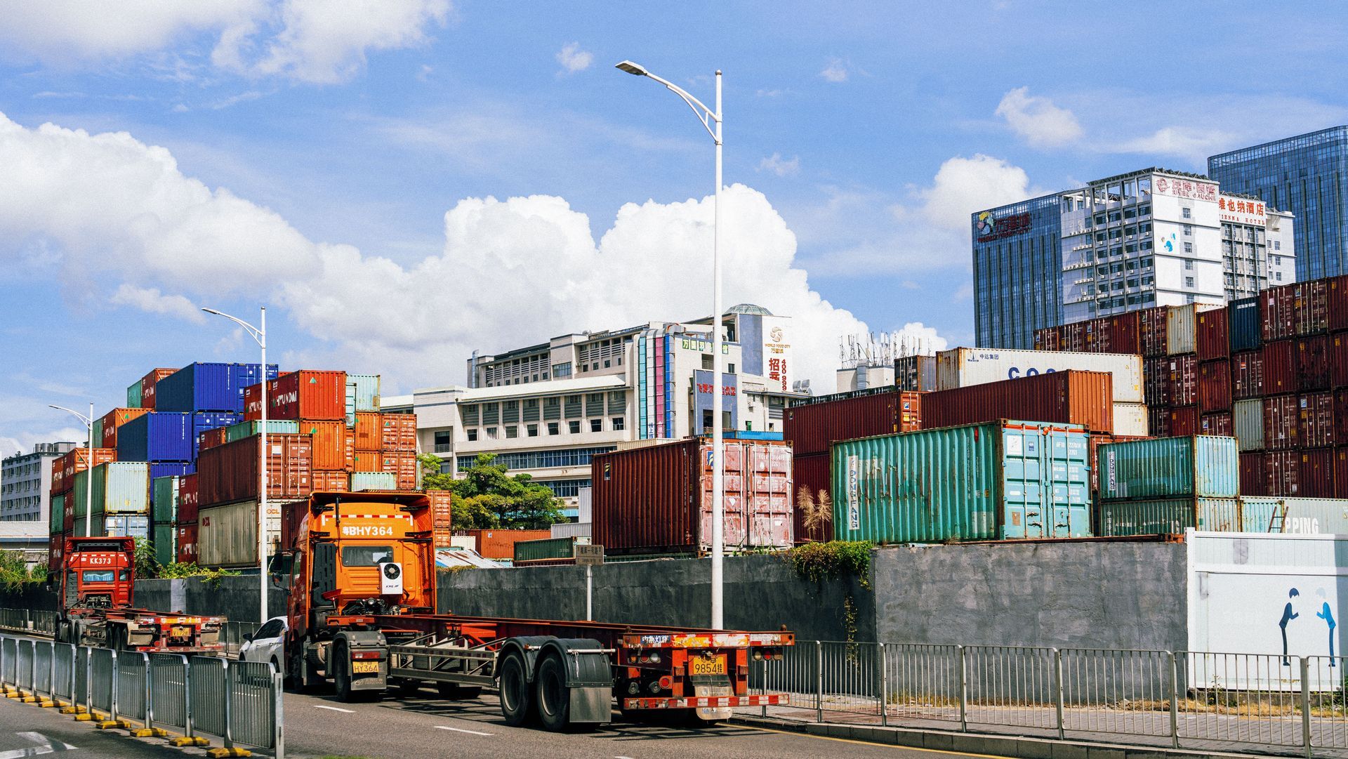 Stacked shipping containers and trucks at a busy port under a cloudy sky — Vent Doors Australia in Bohle, QLD