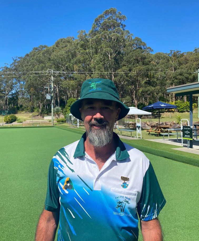 A Man Wearing A Green Hat And A Green Shirt Is Standing On A Green Field — Pacific Palms Bowling Club In Smiths Lake, NSW