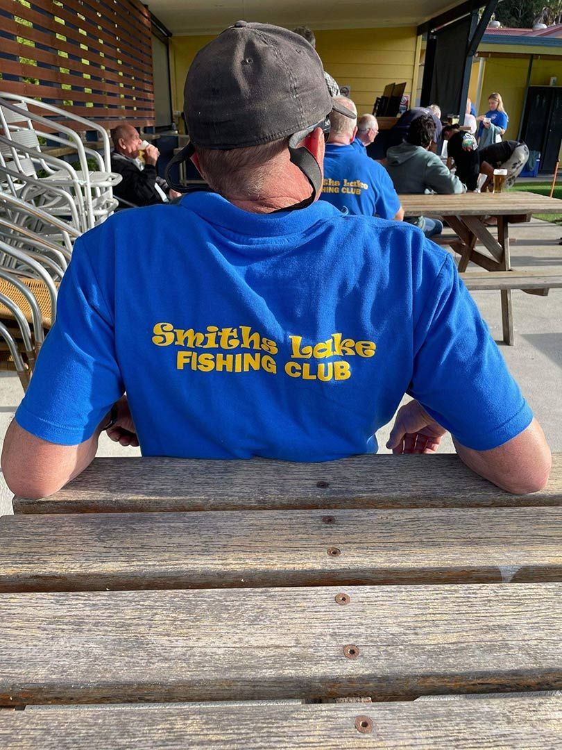 A Man Wearing A Blue Shirt That Says Smith 's Lakes Fishing Club — Pacific Palms Bowling Club In Smiths Lake, NSW