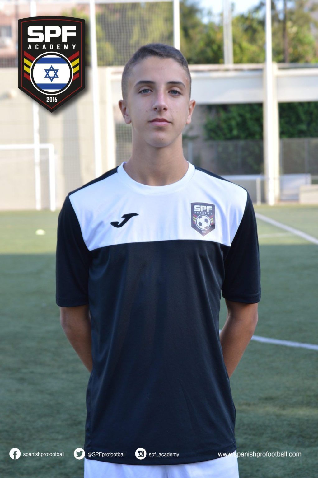 Soccer player in navy and white jersey standing on a field in front of an SPF badge logo