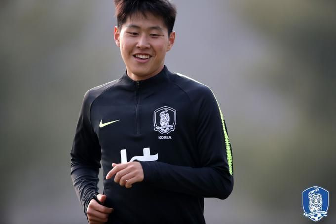 Athlete in black training top jogging outdoors, smiling against a blurred background