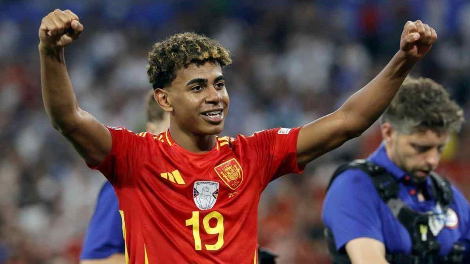Soccer player in red jersey with number 19 raises both arms in celebration on the field