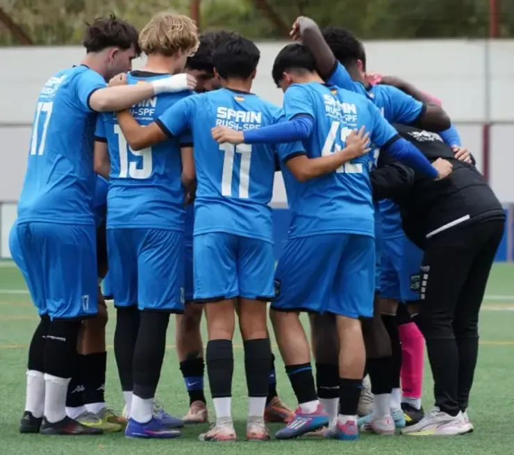 Soccer team in blue uniforms huddles together on the field before the match