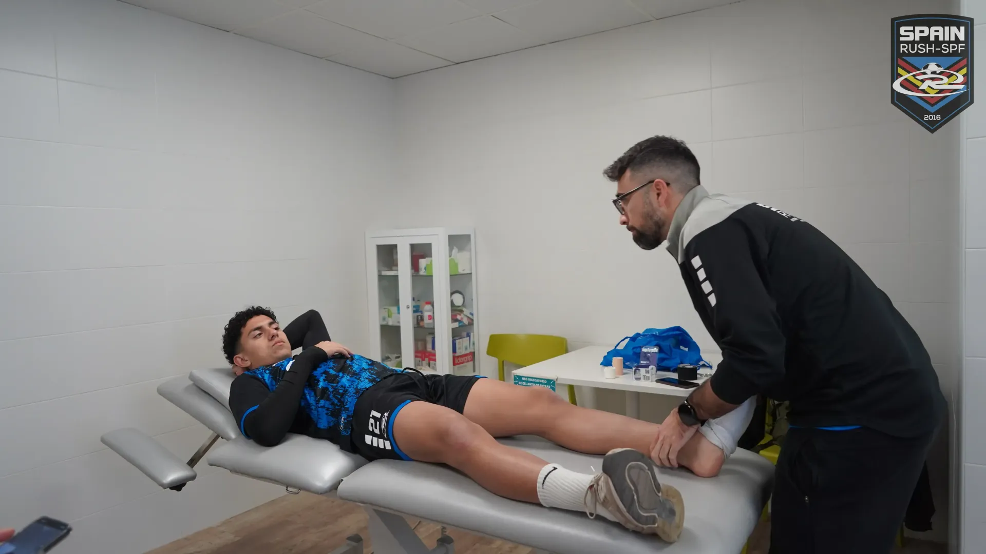 Therapist stretches a patient’s leg on a treatment table in a clinic room.