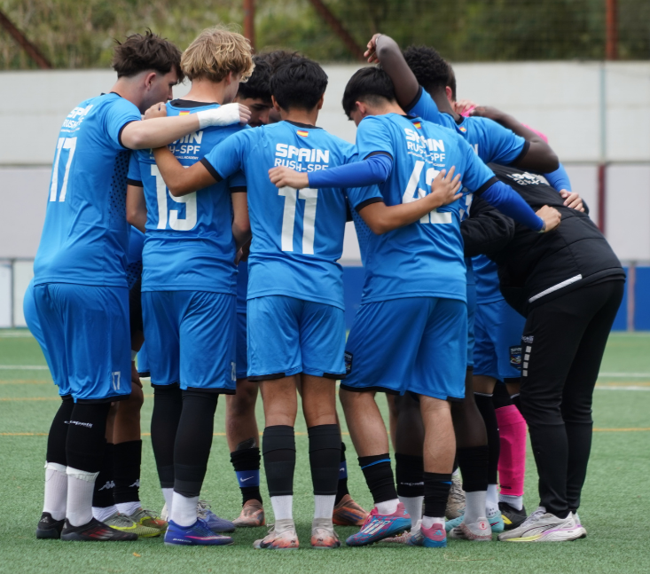 Soccer team in blue uniforms huddles together on the field before the match
