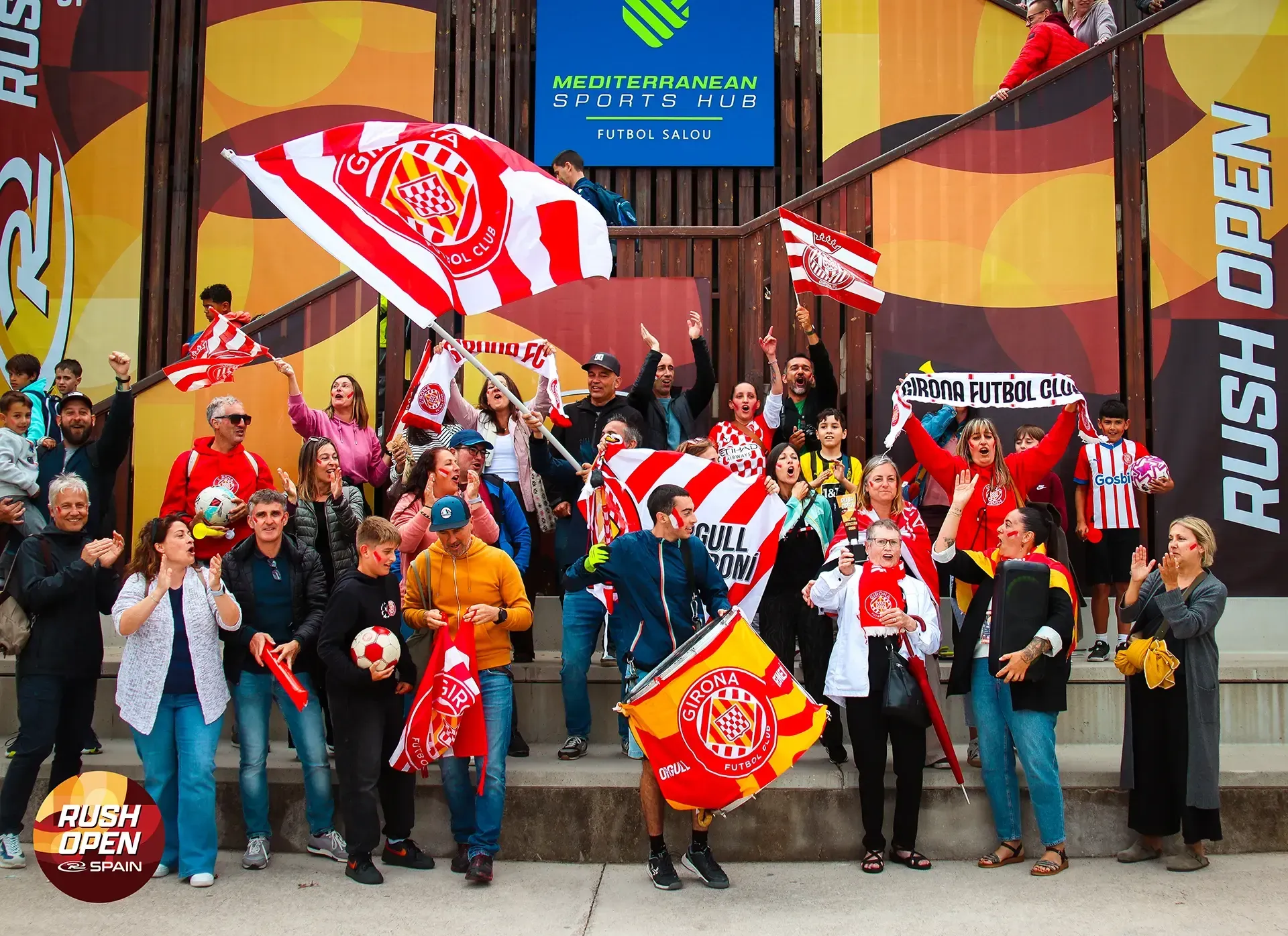 Crowd of hockey fans in red cheering and waving flags outside an arena entrance
