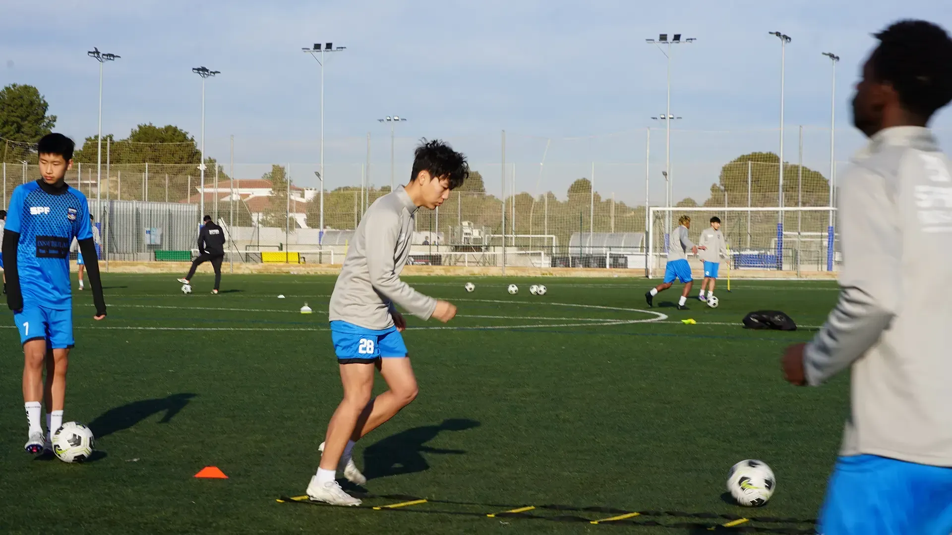 Soccer players training on a field, with cones, balls, and goals in the background.