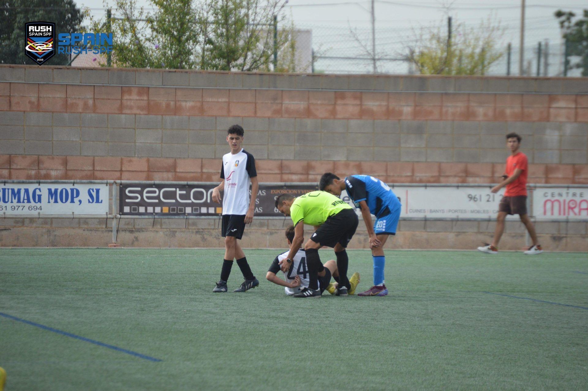Soccer players gather around an injured player on a green field during a match