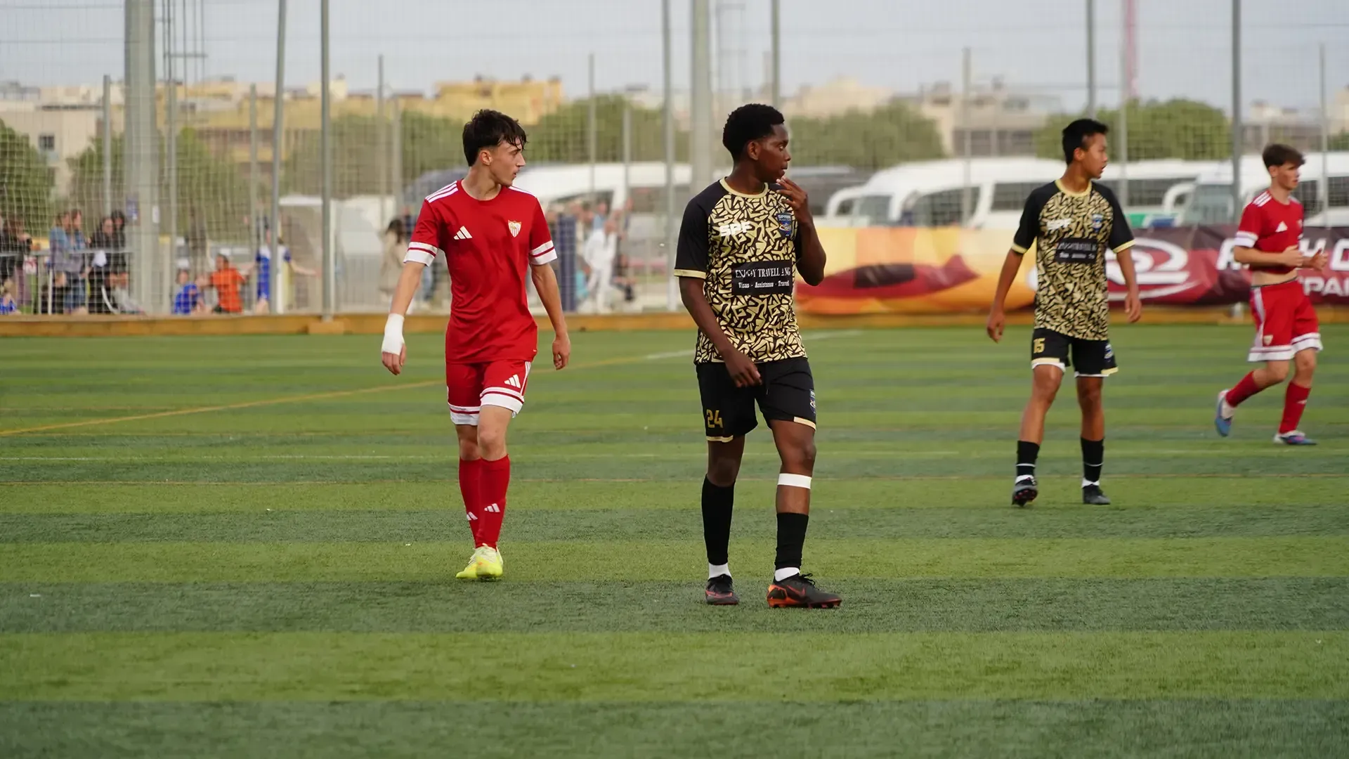 Soccer players in red and black uniforms walking on a field during a match