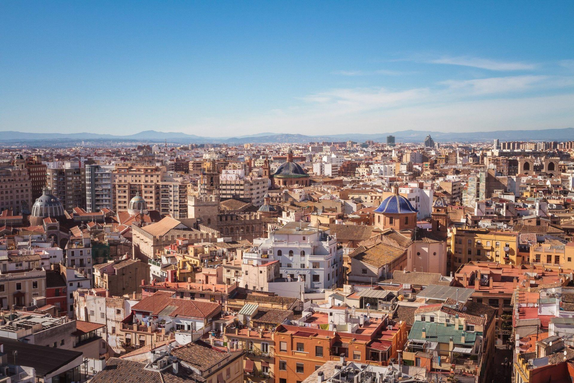 Panoramic view of a dense cityscape with red-roofed buildings under a clear blue sky