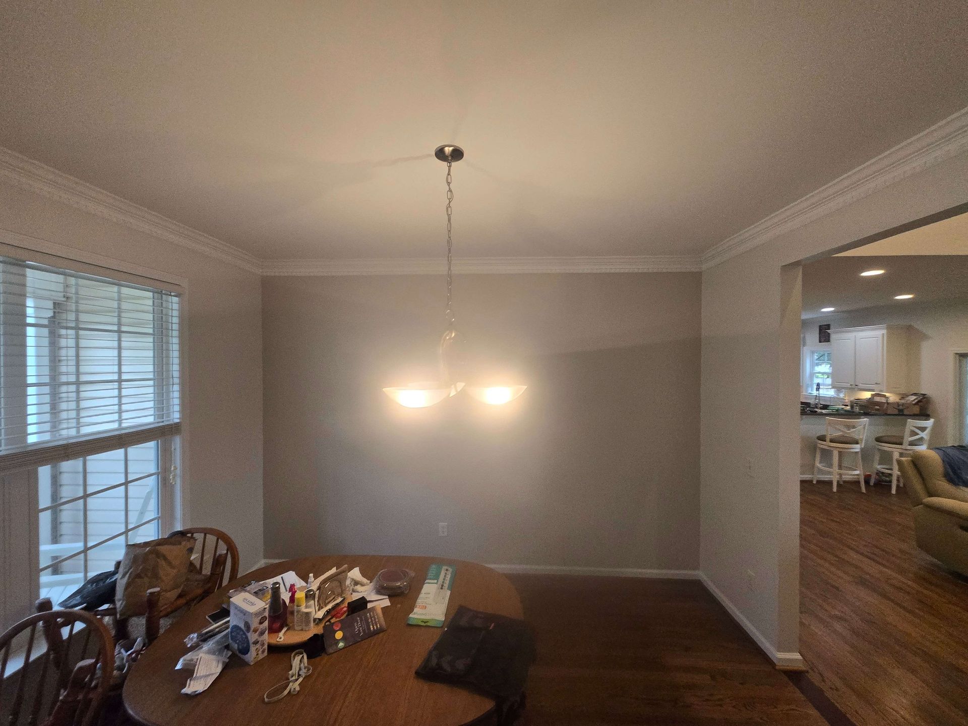 Dining room with a table, hanging light fixture, windows, and an open view into the kitchen.