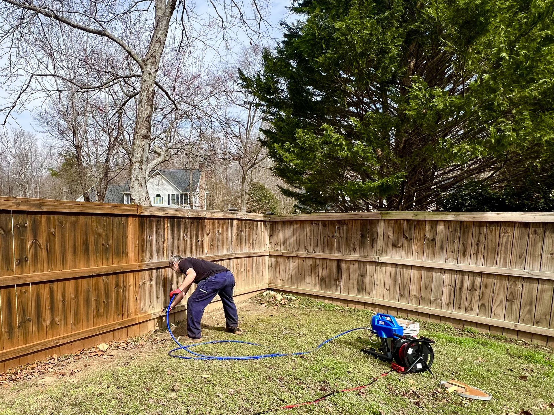 A bright living room space with light wood floors, a dark leather sofa, and an open doorway leading to a staircase.