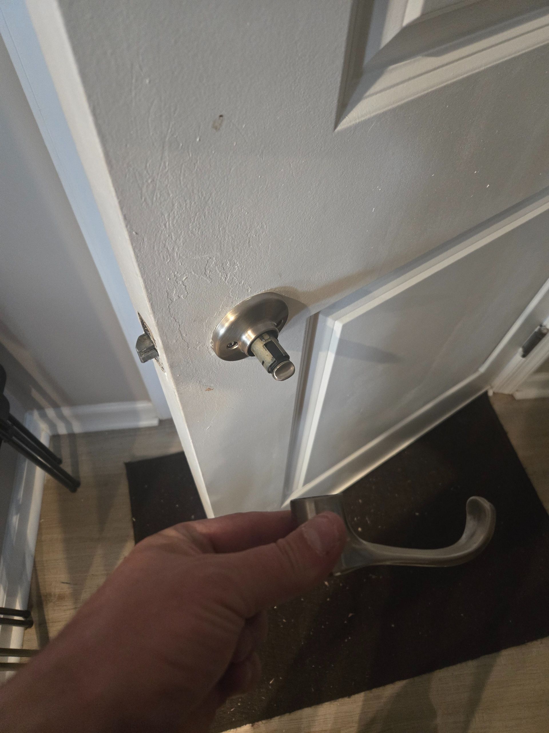 Hand opening a white door with a silver handle, viewed close up from inside.