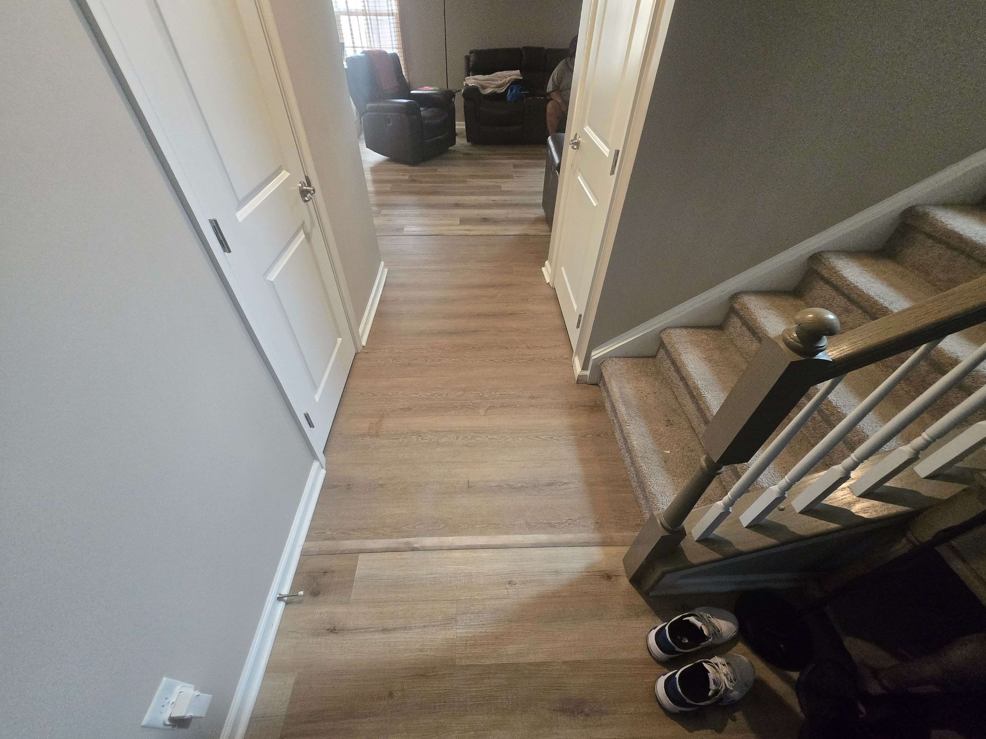 Hallway with wood floor, staircase on the right, and open door leading to a room ahead