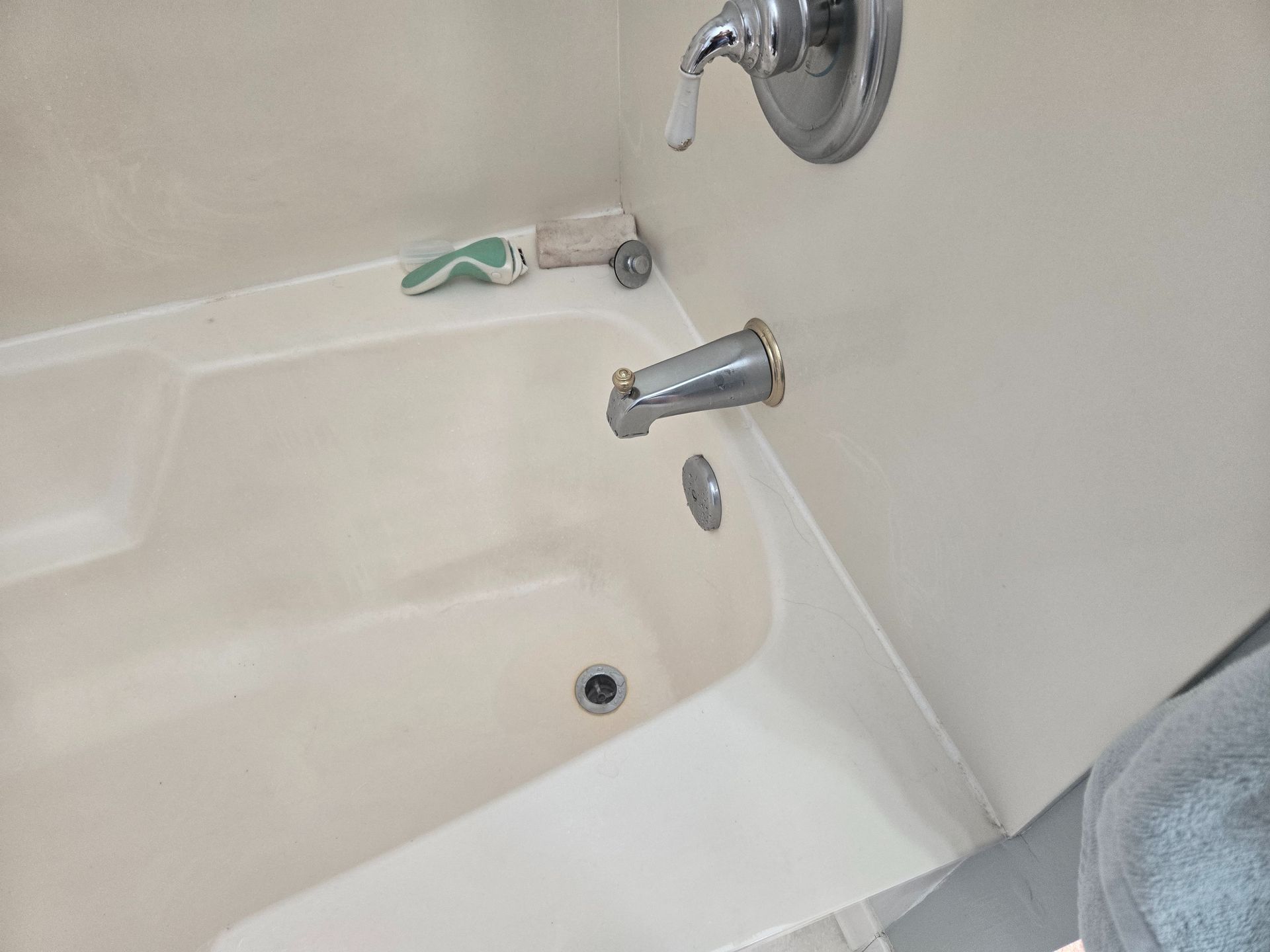 Bathtub with wall-mounted faucet and tub spout; a small object rests on the ledge.