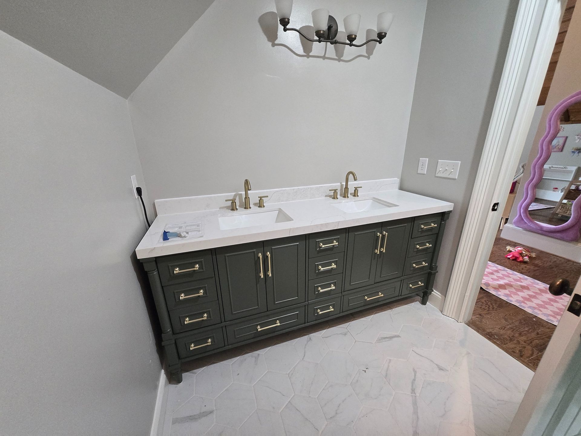 Bathroom vanity with dark cabinets, white countertop, twin sinks, and mirror lights