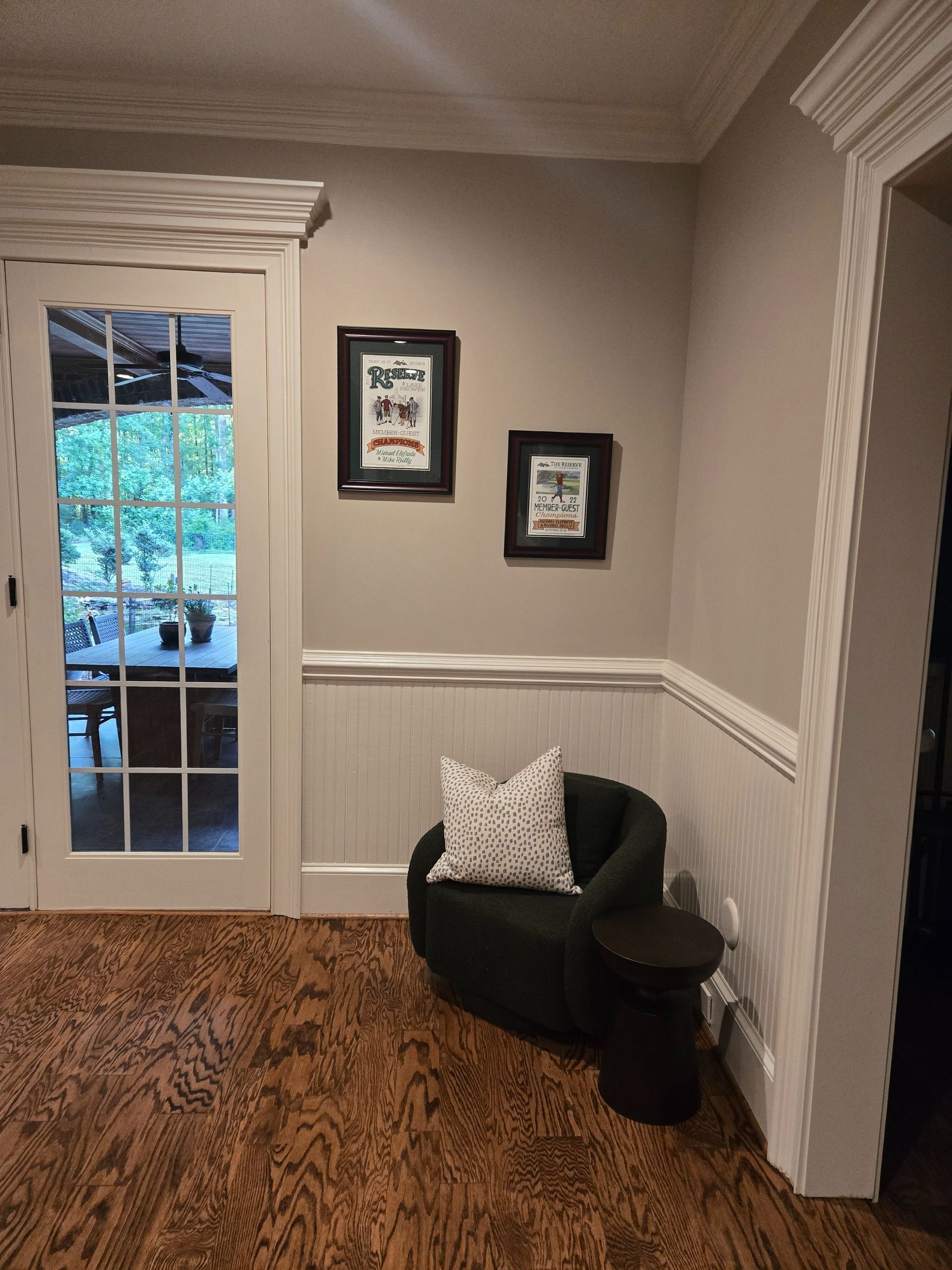 Entryway with dark green chair, patterned rug, framed art, and glass door with view outside.