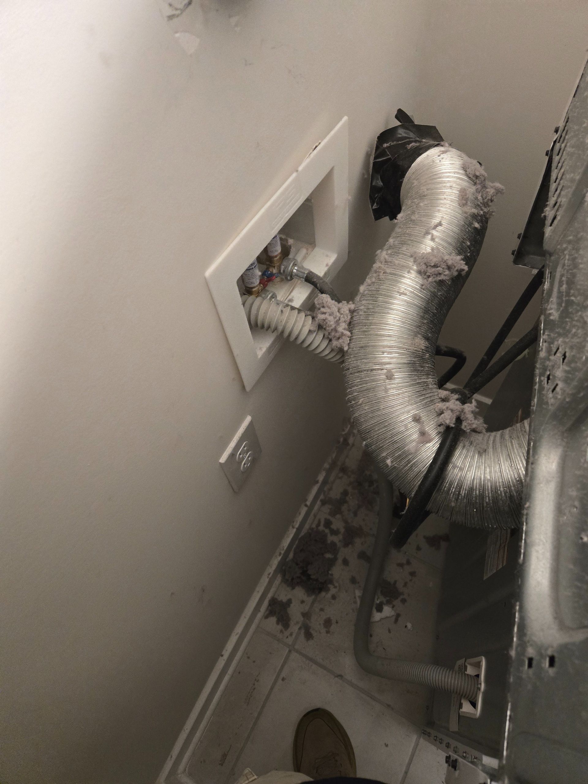 Wall cavity with insulated ducting and exposed vent connection behind a dryer or HVAC unit.
